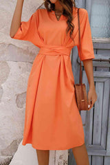 a woman wearing an orange dress and hat