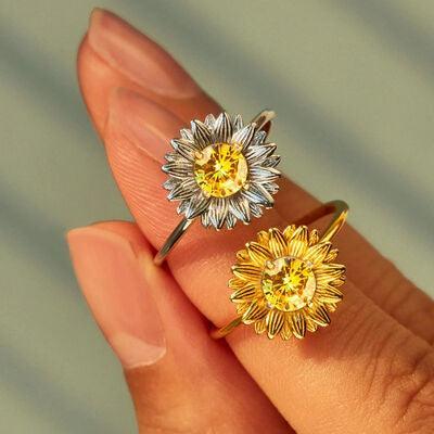 a woman's hand holding two yellow and white flowers