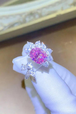 a woman's hand holding a pink diamond ring