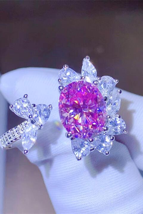 a pink and white diamond ring sitting on top of a white glove