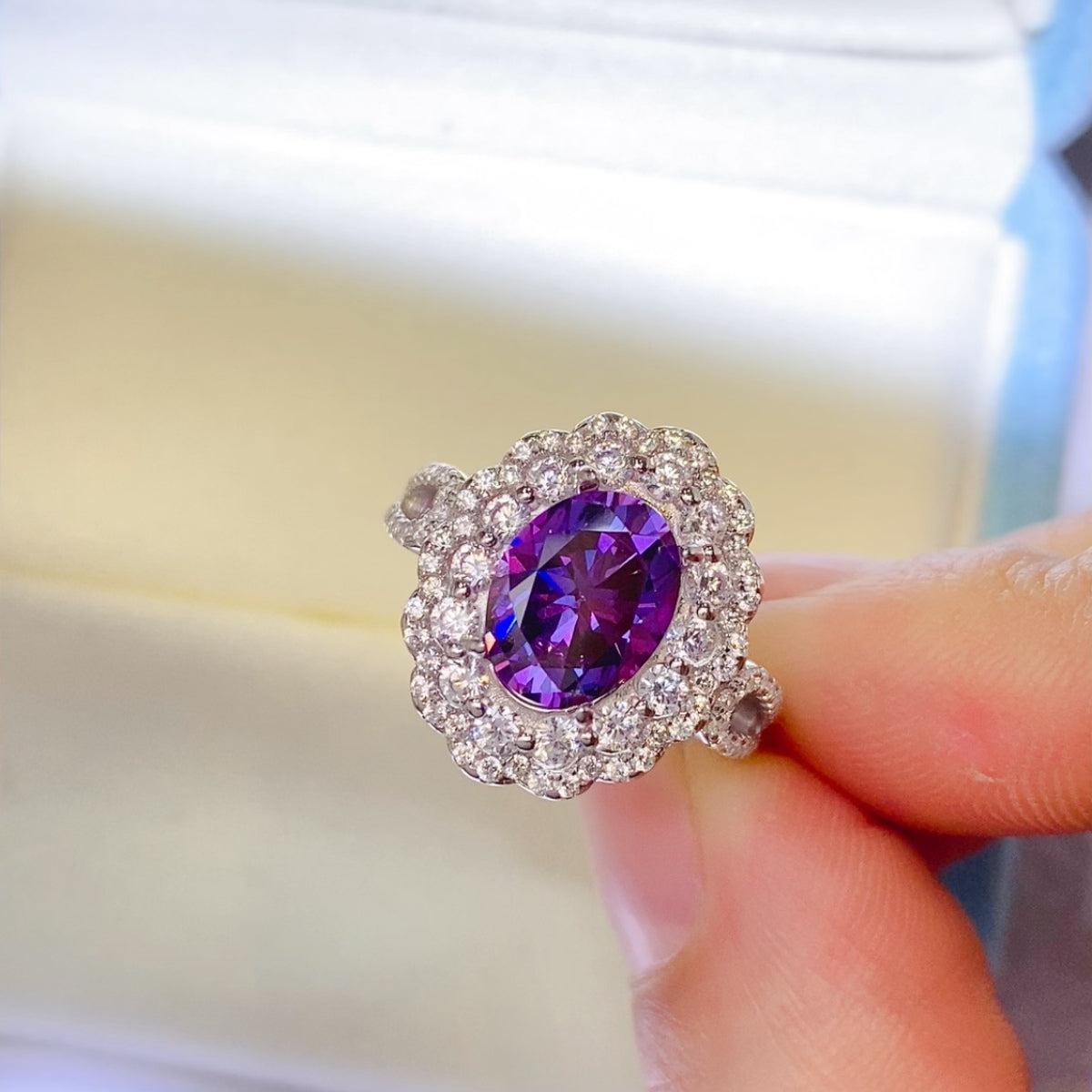 a person holding a ring with a purple stone in it