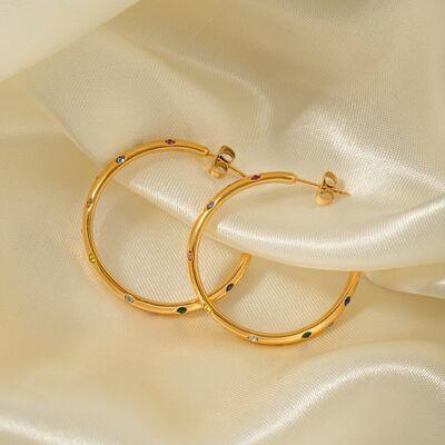 a pair of gold hoop earrings sitting on top of a white cloth