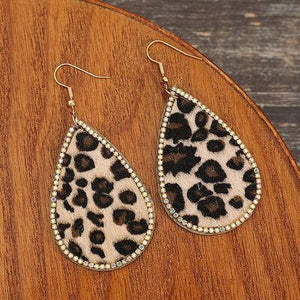 a pair of leopard print earrings on a wooden surface