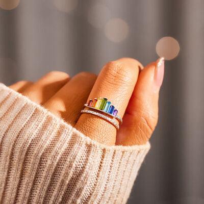 a woman's hand with a rainbow ring on it