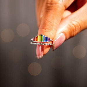 a woman's hand holding a multicolored ring