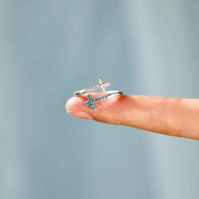 a person holding a tiny ring with a cross on it