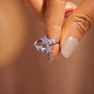 a woman's hand holding a ring with flowers on it