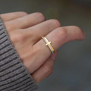 a woman's hand with a gold ring with a cross on it