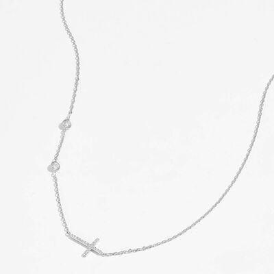 a silver cross necklace on a white background