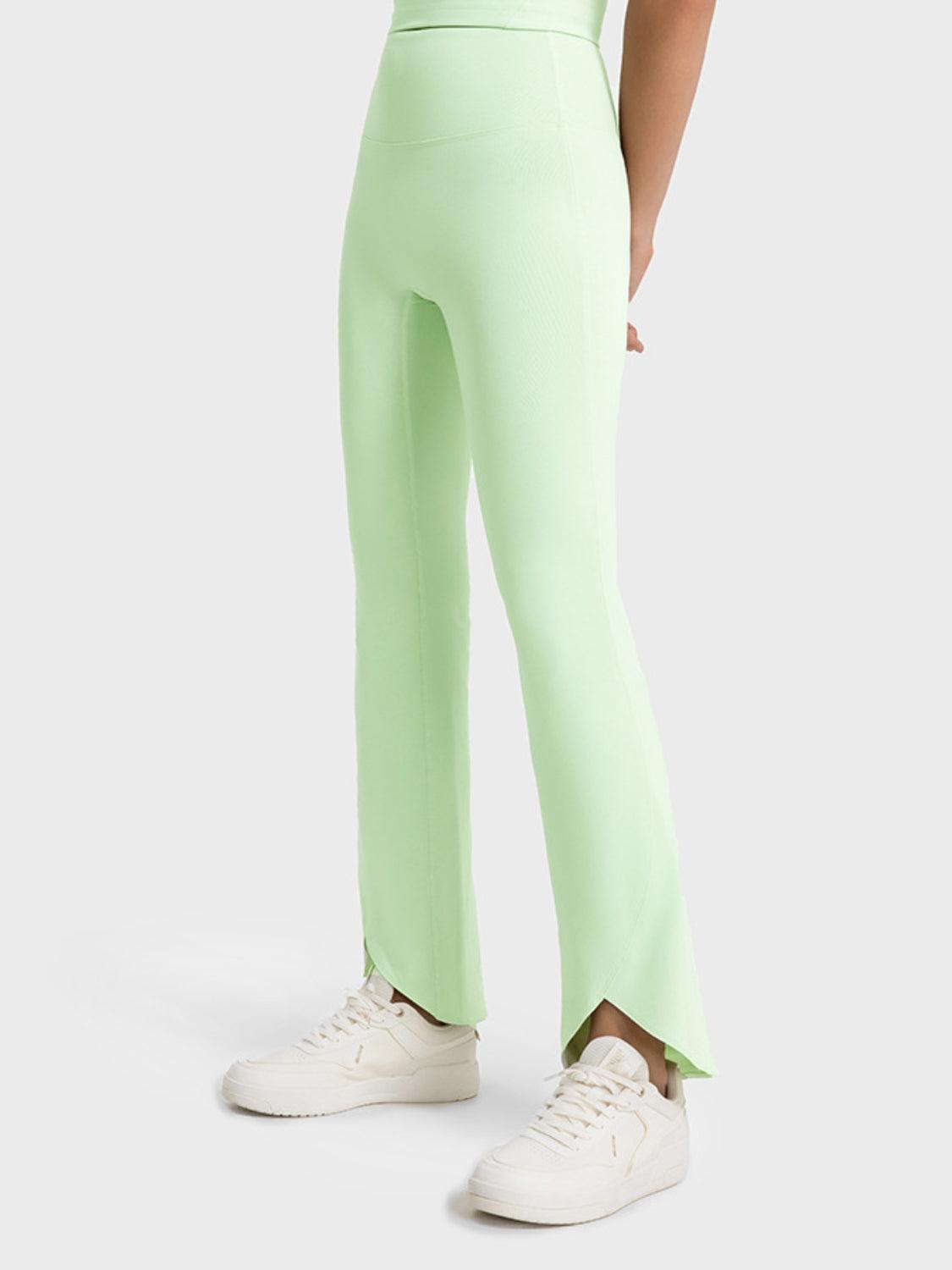 a woman in a white top and green pants