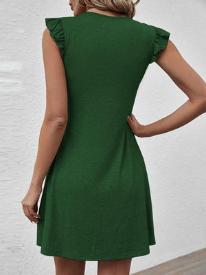 a woman wearing a green dress with ruffles on the back