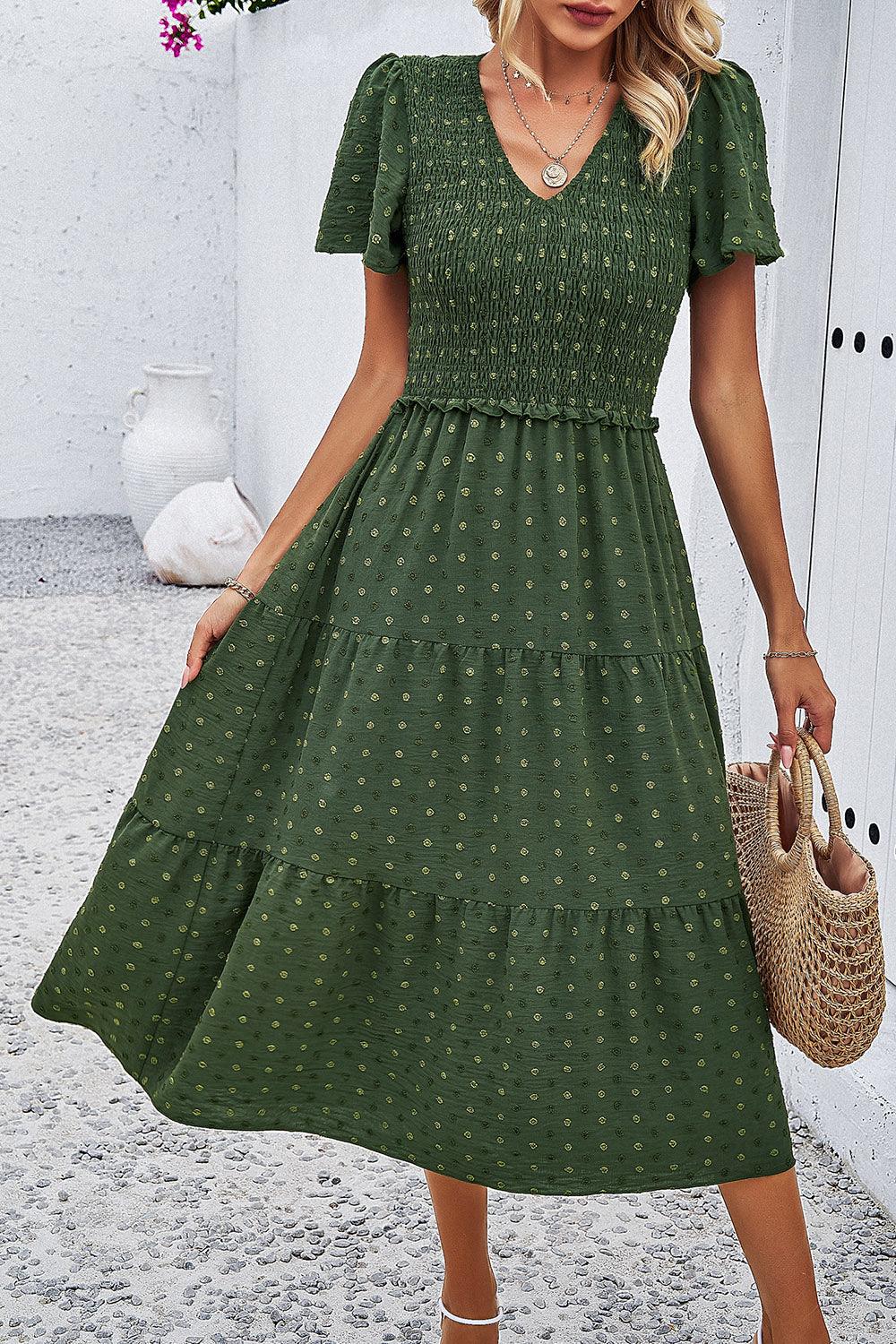 a woman in a green dress holding a straw bag