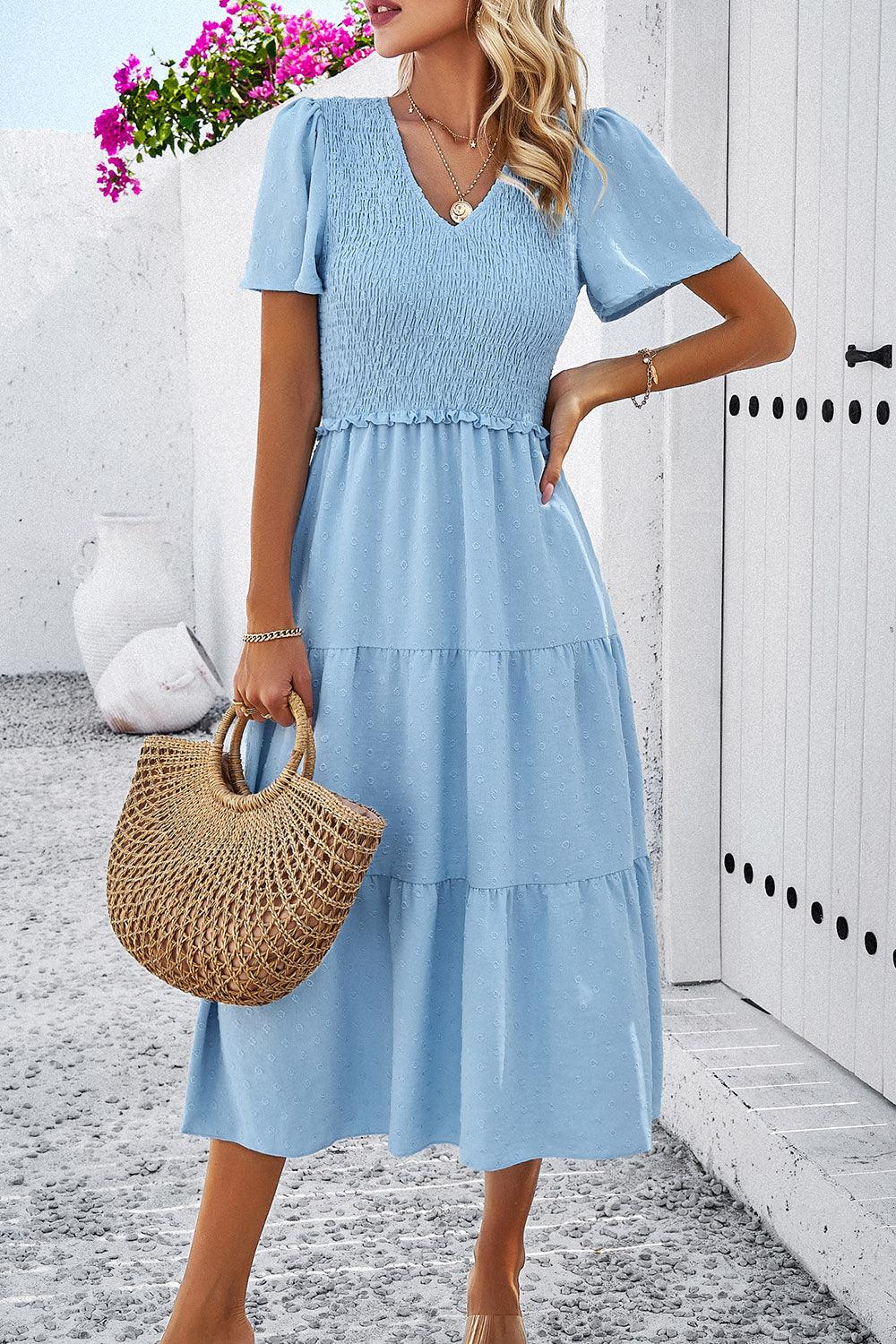 a woman in a blue dress holding a straw bag