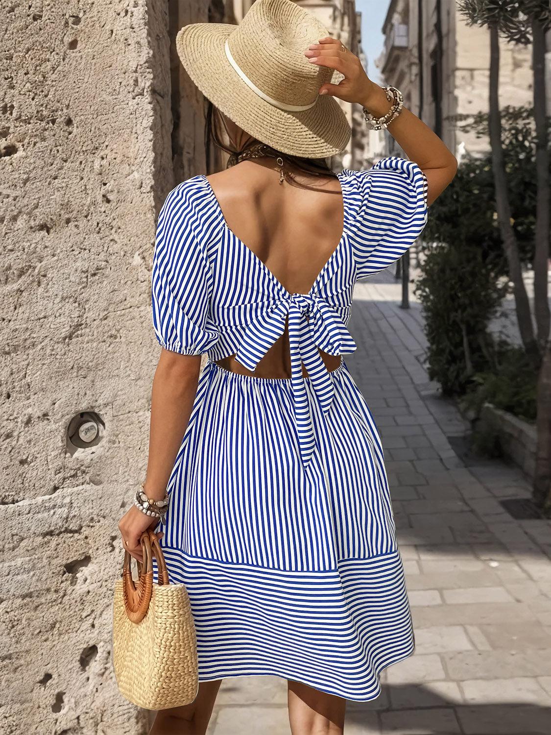 a woman wearing a blue and white striped dress and a straw hat
