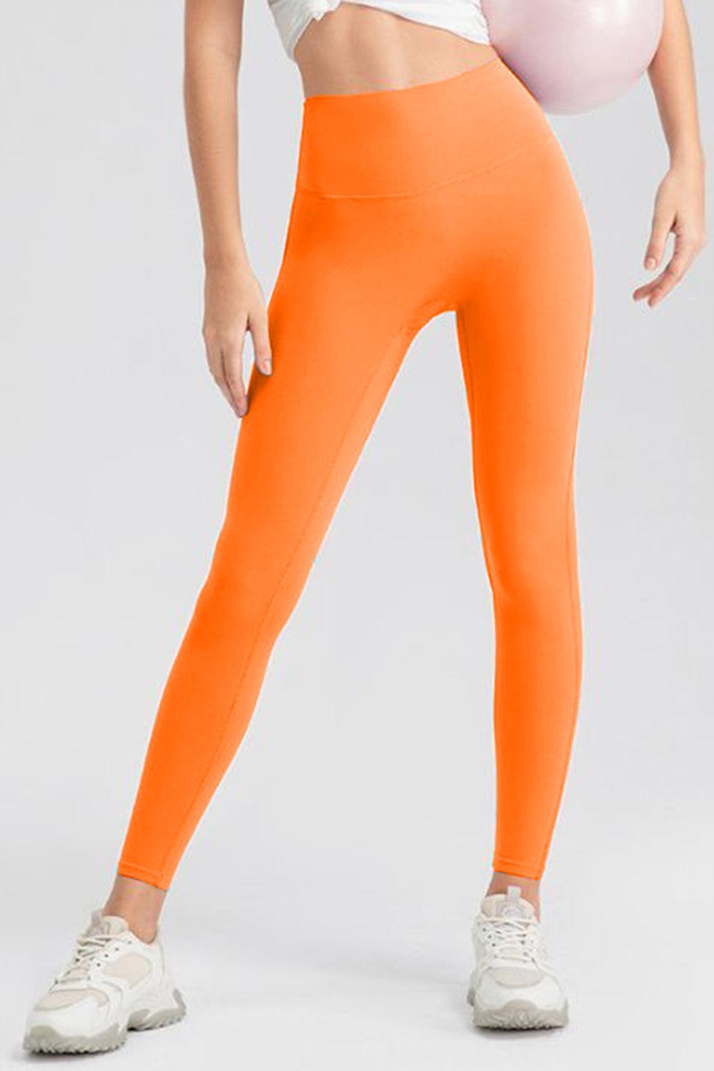 a woman in an orange leggings holding a pink ball