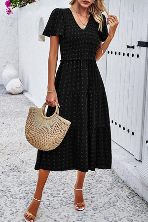 a woman in a black dress holding a straw bag