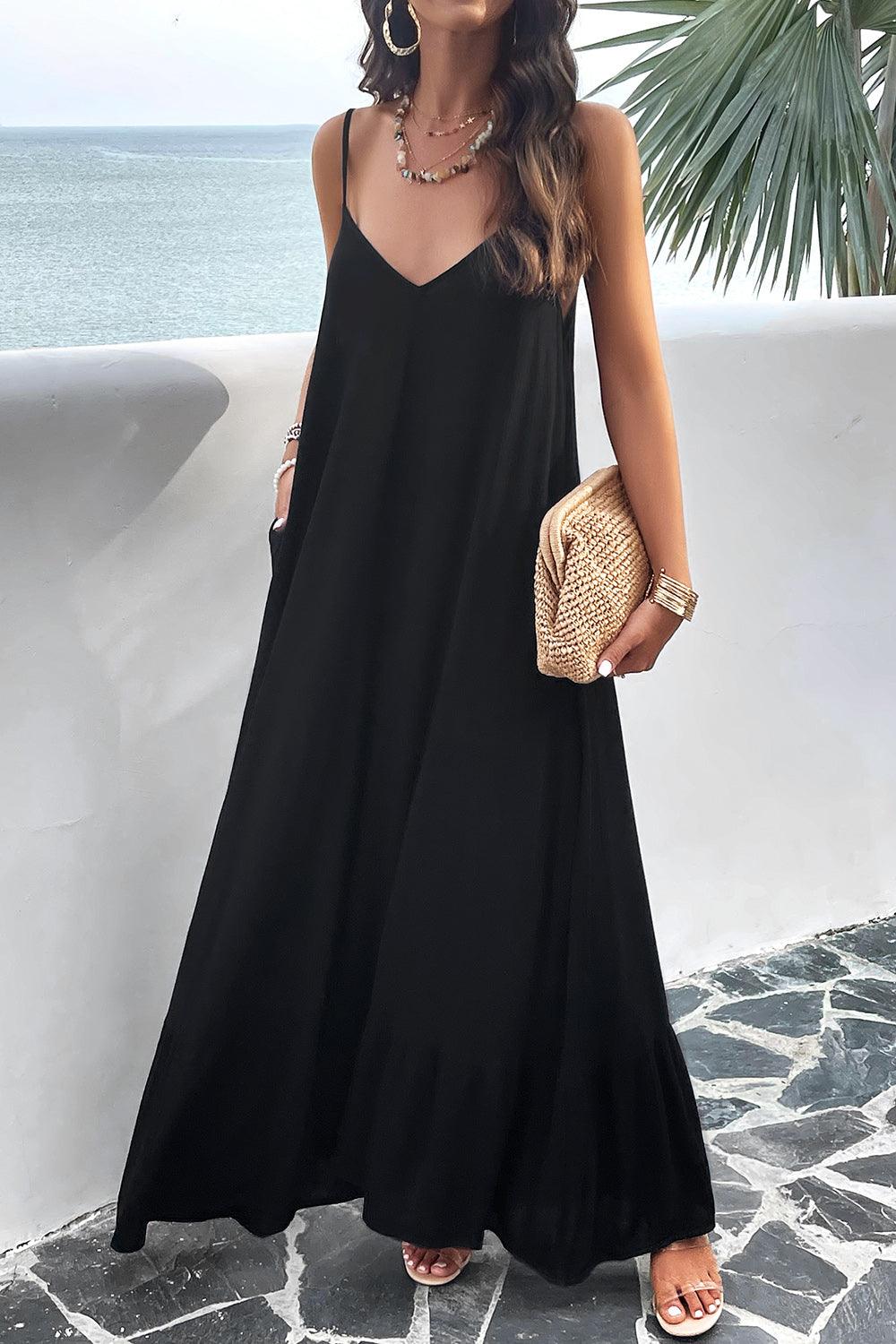a woman in a black dress standing by the ocean